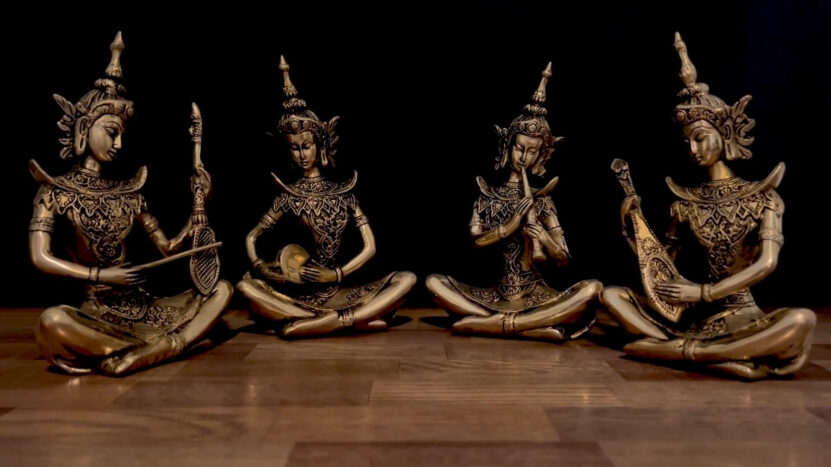 Antique brass figurines of four seated musicians playing traditional instruments